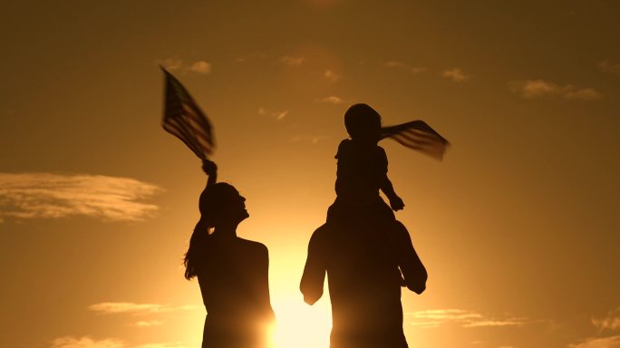 挥舞着美国国旗的幸福家庭。独立日。