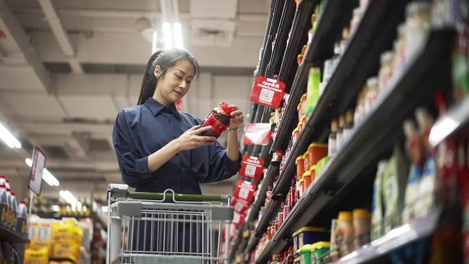 年轻中国女性在超市选购调味品