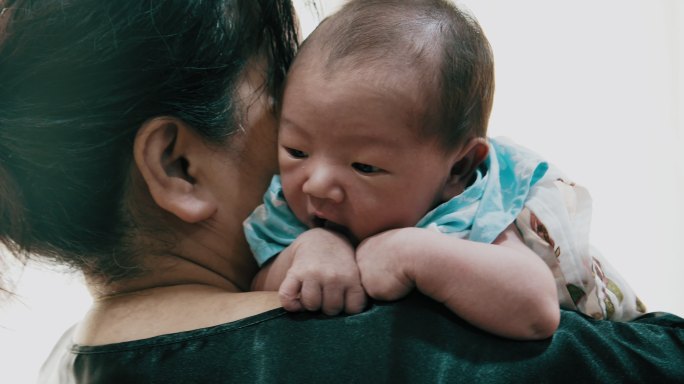 躺在祖母肩上的可爱男婴