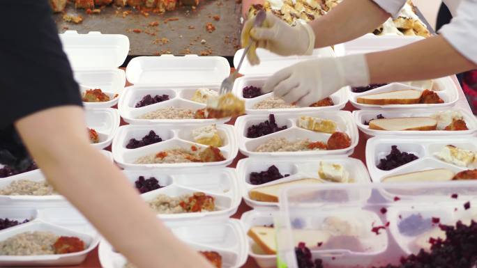 特写镜头，志愿者将免费热餐装在午餐盒里