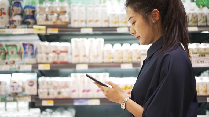 年轻中国女性在超市使用手机购物