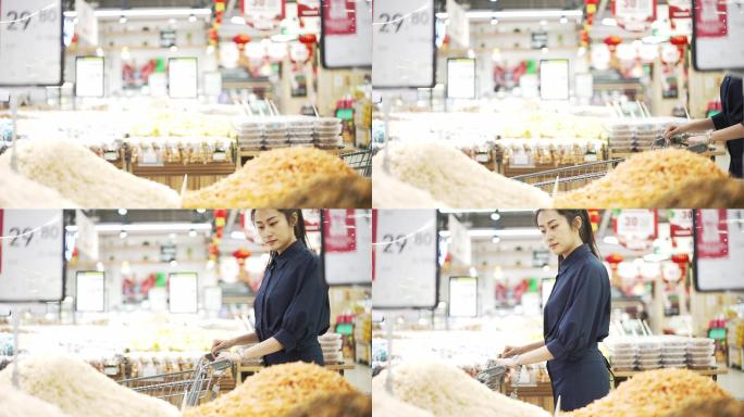 年轻中国女性推着小推车在超市购物购买大米