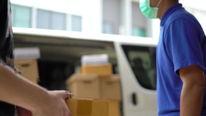 戴医用橡胶手套的送货员向客户发送包裹