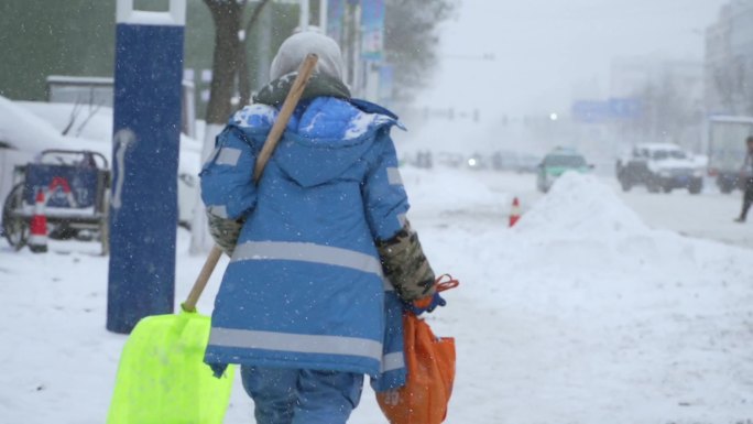 环卫工人在雪中艰难行走背影