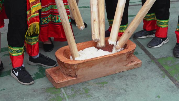 广西壮族特色打米糕，一群人用木棒锤糯米