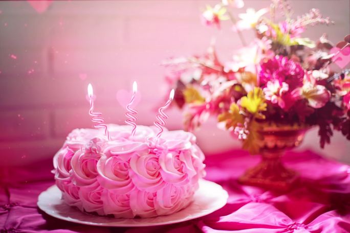 粉红色的生日蛋糕上燃烧的蜡烛