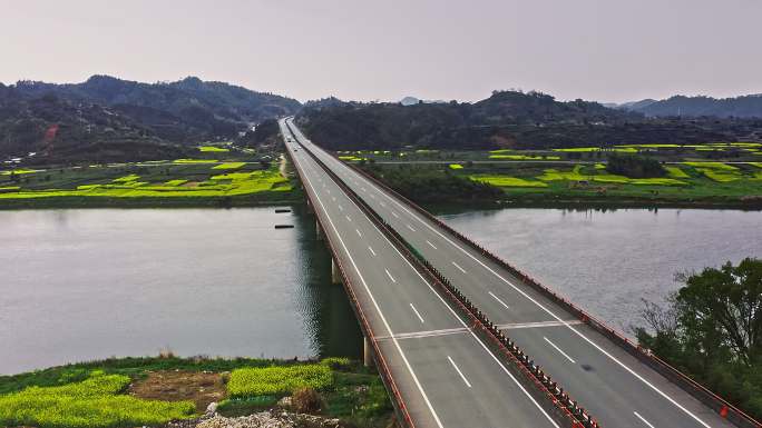 4K航拍高速公路穿过油菜花田和大江