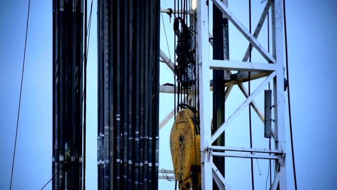 一名工人爬上压裂钻机调整电线和软管。