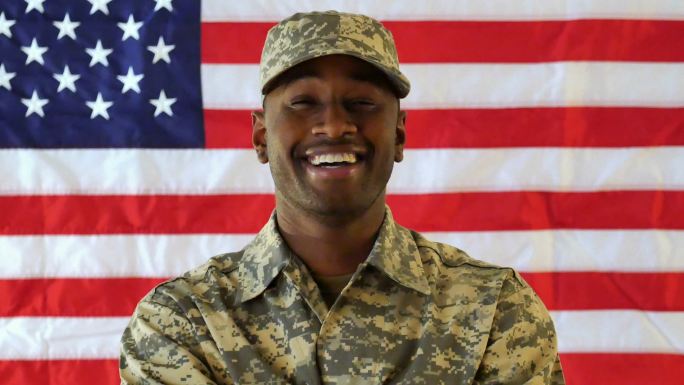 美国士兵站在美国国旗前自信地微笑