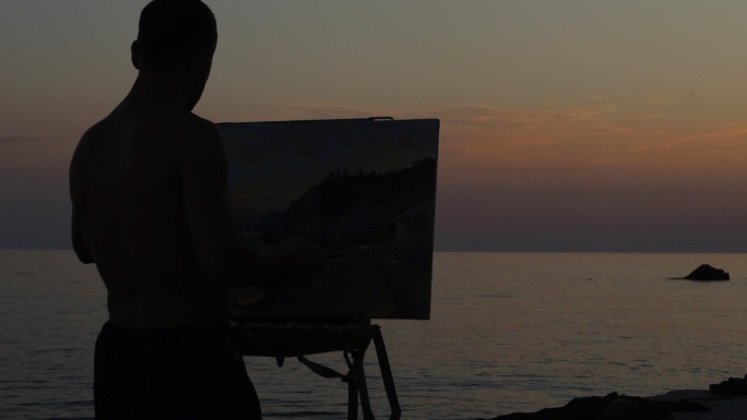 在岩石海绘制美岸丽落日的艺术家