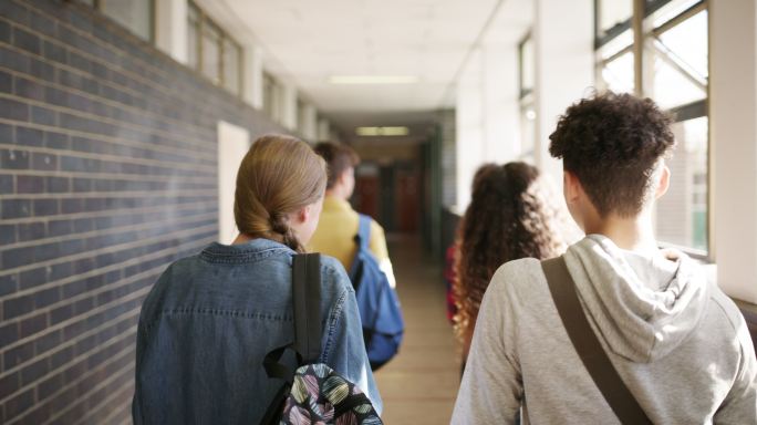 一组十几岁的学生穿过高中大厅
