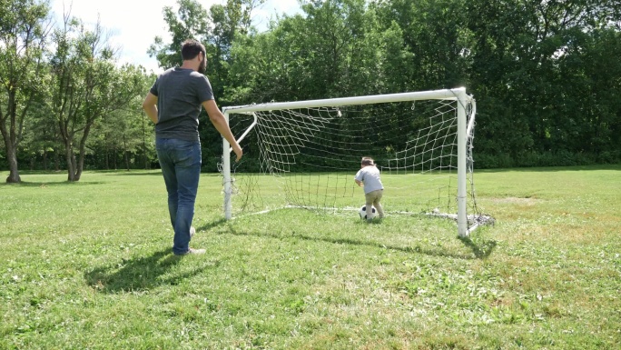 年轻的父和他亲的小儿子在足球场上踢足球