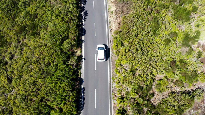 白色家用汽车通过直道沥青路面的无人机镜头