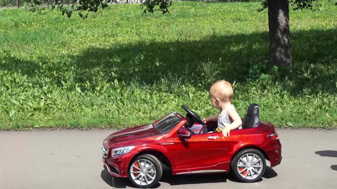 小男孩正在骑一辆由父亲驾驶的玩具车