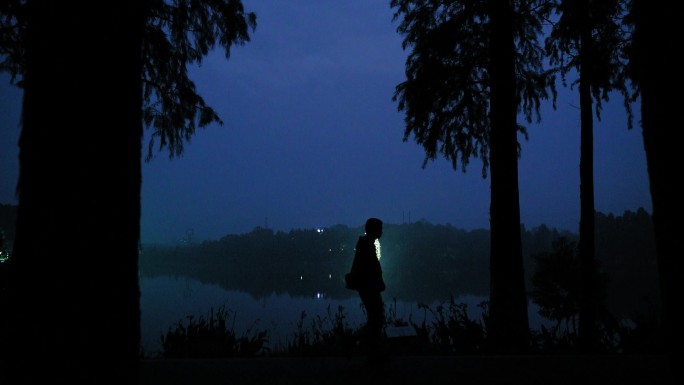 夜晚湖边走路的男人身影