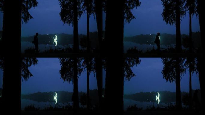 夜晚湖边走路的男人身影