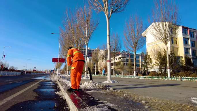 4k拍摄夕阳下环卫工人清扫马路边的积雪