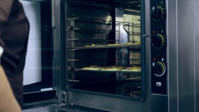 厨师将食物放入一个大型工业烤箱