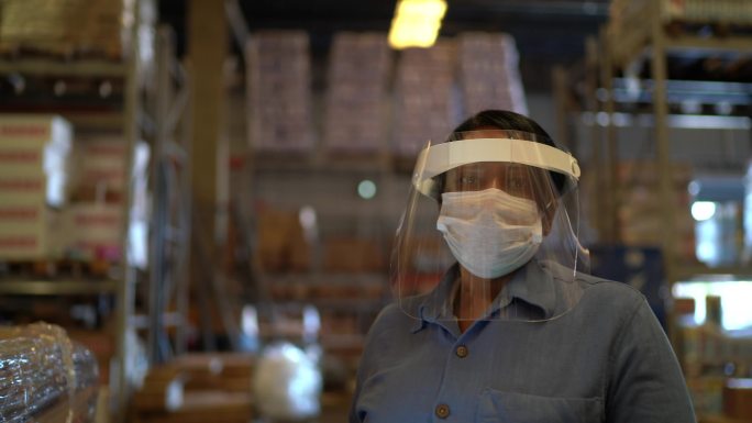 使用数字平板电脑带口罩的女仓库工人