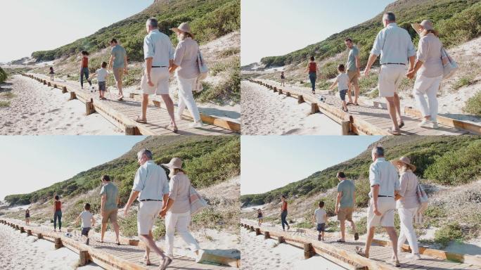 一家在暑假沿着木制木板路去海滩