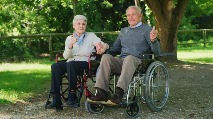 一对坐在轮椅上的老年夫妇手牵着手