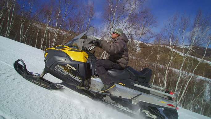 外国游客在滑雪场驾驶摩托雪橇快速速行驶