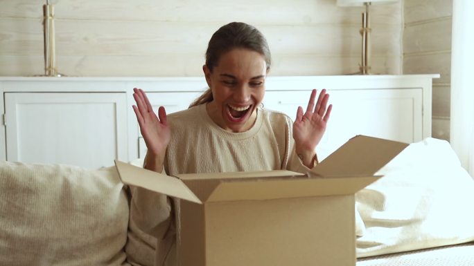 兴奋的年轻女子消费者打开纸箱领取邮包