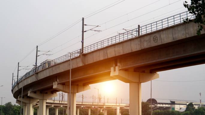 德里地铁列车在日落时分通过大桥