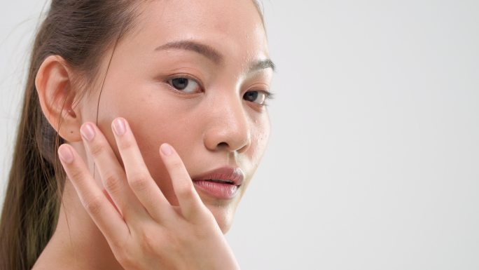 亚洲女性用美容护肤品摩擦皮肤。