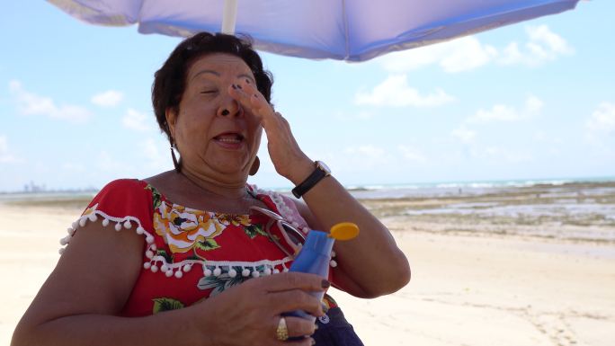 在海滩上使用防晒霜的女人