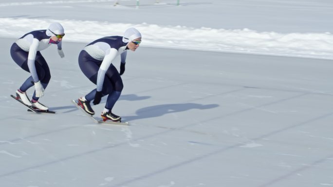 两名运动员在室外溜冰场的跑道上练