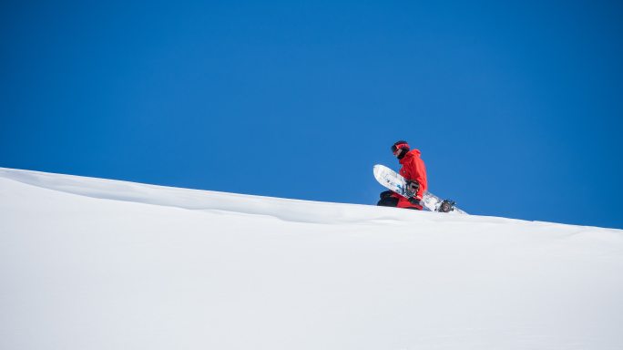 年轻人拿着滑雪板行走在雪原的风景