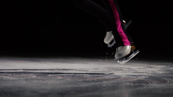 穿着冰鞋的双腿在冰上跳起并落地