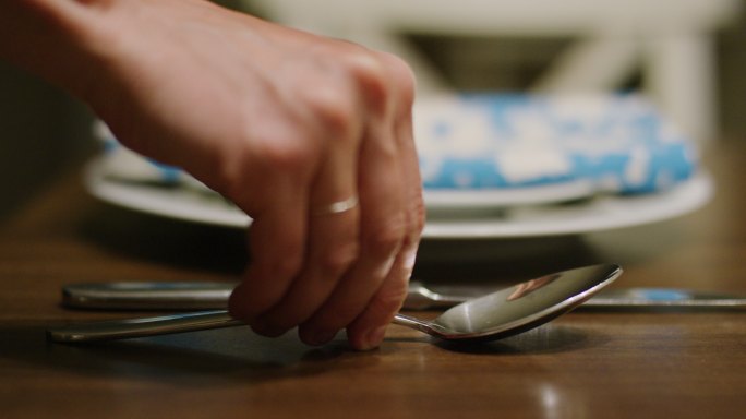 手把勺子放在木桌上的桌刀旁边