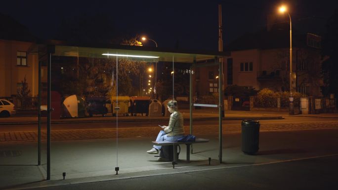 晚上在公共汽车站候车亭等候的女孩
