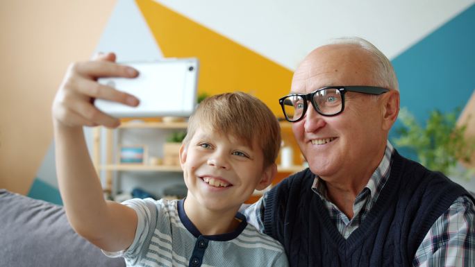 老人和男孩在家自拍用智能手机摆出姿势