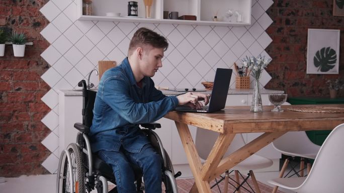 坐轮椅的年轻人在家里电脑