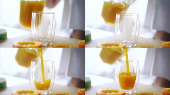 一个女人把橙汁从玻璃罐里倒进玻璃杯里