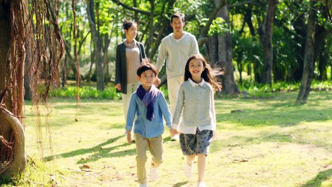 亚洲家庭带着两个孩子在公园散步