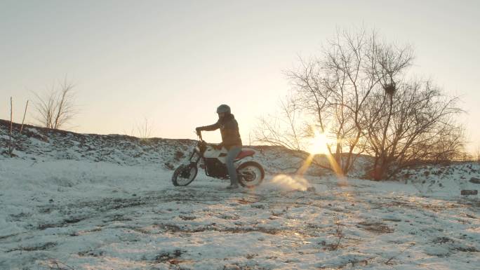 日落时分，专业的摩托车手在雪地上滑行和转弯