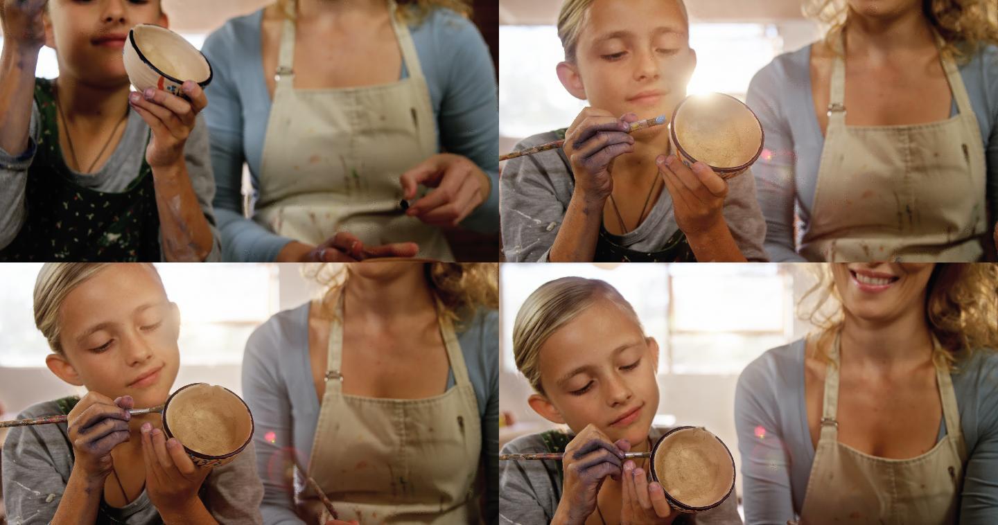 母亲在陶器作坊协助女儿画碗