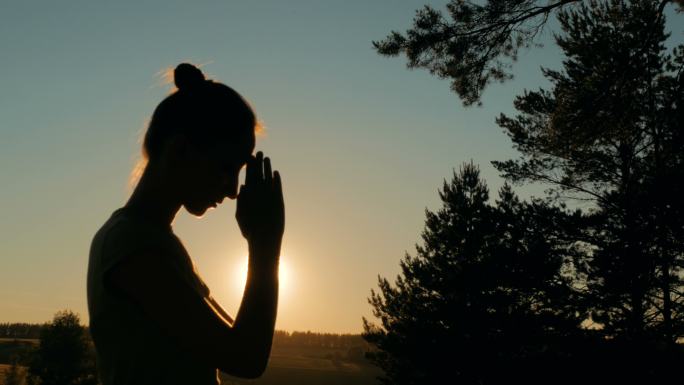 日落时在森林里祈祷的女人