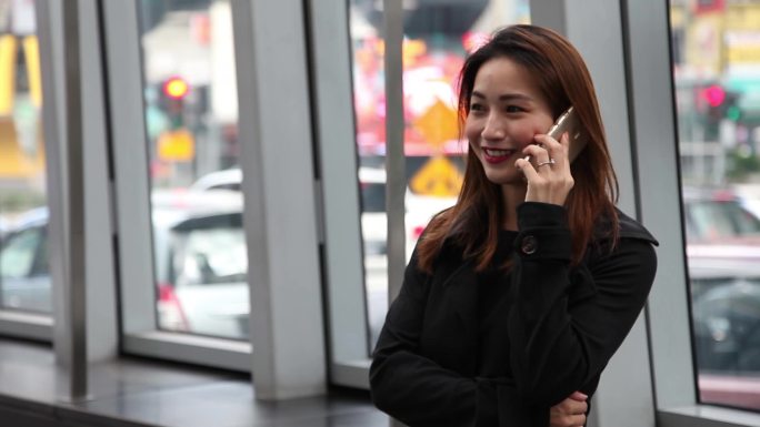 亚洲华裔女人在繁忙的街道上打电话