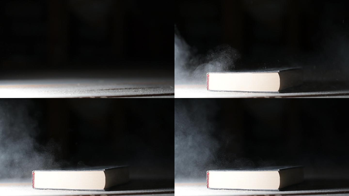 一本书落在满是灰尘的地板上，扬起了灰尘