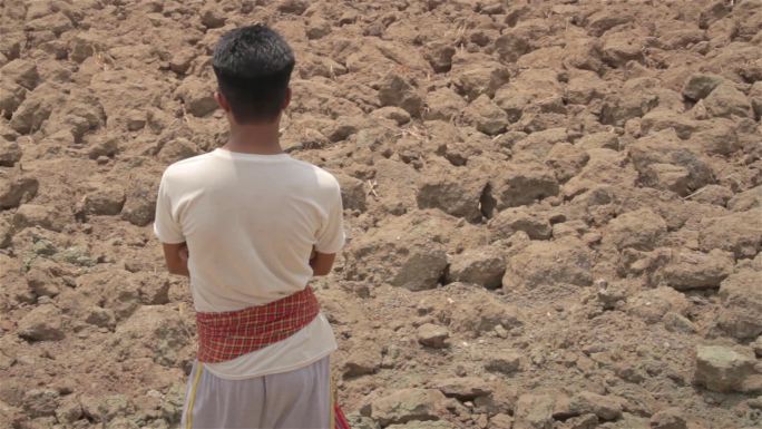 饱受摧残的印度农民站在干涸的土地上