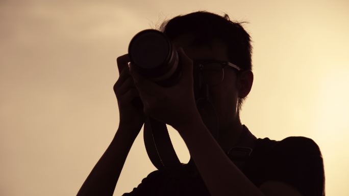 剪影摄影师使用带长焦镜头的照相机拍照。