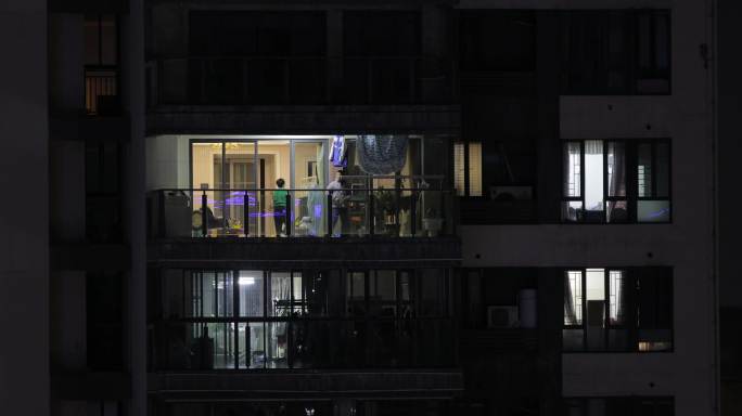 夜晚居民小区窗户阳台忙碌的家人居民
