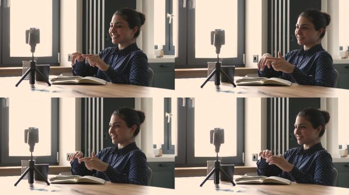 一名印度妇女坐在办公桌旁用手机录视频