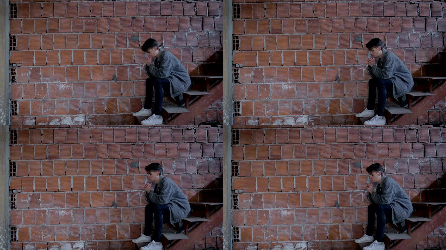 悲伤的少年坐在砖墙旁