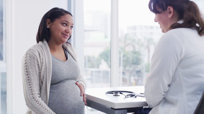 年轻女医生在办公室与怀孕患者讨论